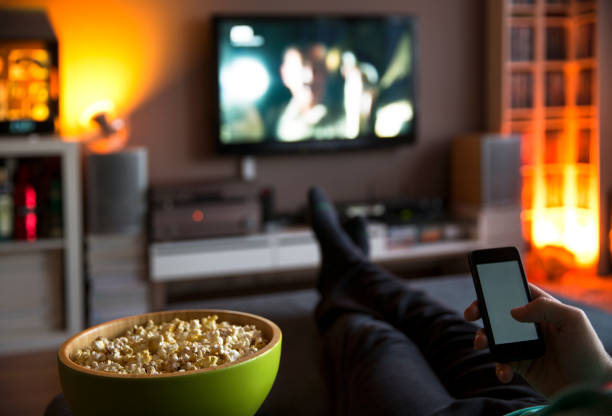 mens die thuis het letten op tv let en popcorn eet en internett - watching tv stockfoto's en -beelden