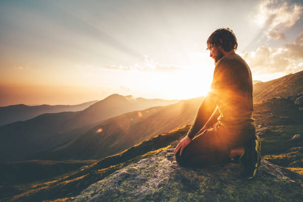 Man relaxing at sunset mountains Travel Lifestyle spiritual awakening emotional meditating concept vacations outdoor harmony with nature landscape stock photo