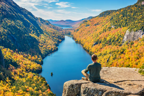 Man relaxing in Adirondack Mountains New York State USA during Fall colors Man enjoys view in the Adirondack Mountains, New York State, USA, on a sunny day during Fall colors. adirondack state park stock pictures, royalty-free photos & images
