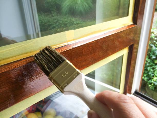 Man repaint a window frame Man repaint a window frame with brown varnish lacquered stock pictures, royalty-free photos & images