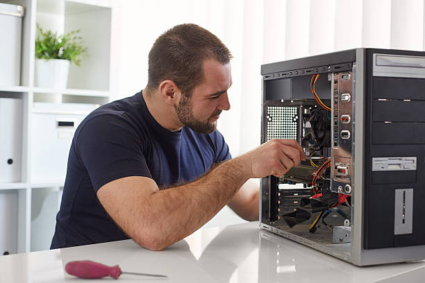 Man repairing computer Young man repairing computer while sitting at his working place computer part stock pictures, royalty-free photos & images