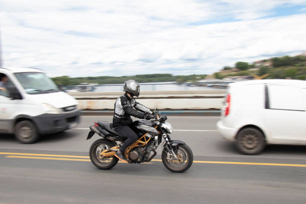 mann fährt motorrad im verkehr, über die stadtbrücke - motorrad fluss stock-fotos und bilder