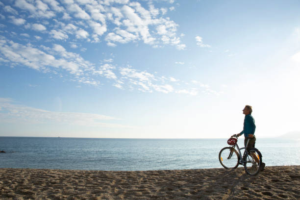Man riding bicycle relaxes on beach in the morning He looks off to Mediterranean Sea in the distance cirrostratus stock pictures, royalty-free photos & images