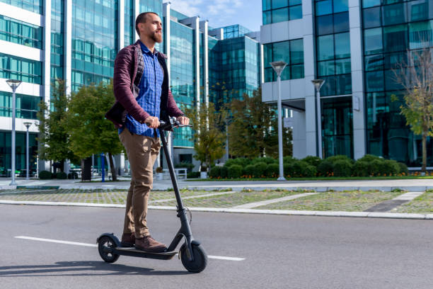 Man riding scooter through modern city stock photo