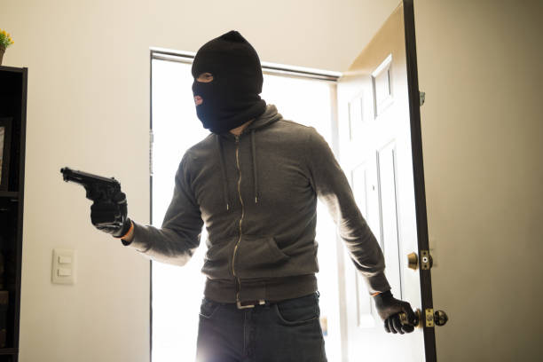 Man robbing house with a gun Male robber with a gun and a ski mask entering private property to steal ski mask criminal stock pictures, royalty-free photos & images