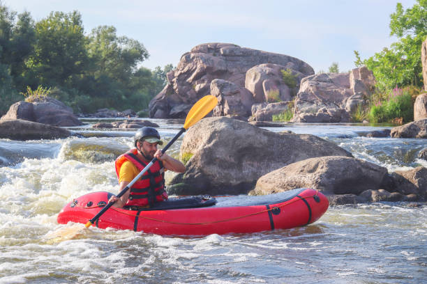 A man rowing inflatable packraft on whitewater of mountain river. Concept: summer extreme water sport,  active rest, extreme rafting. stock photo