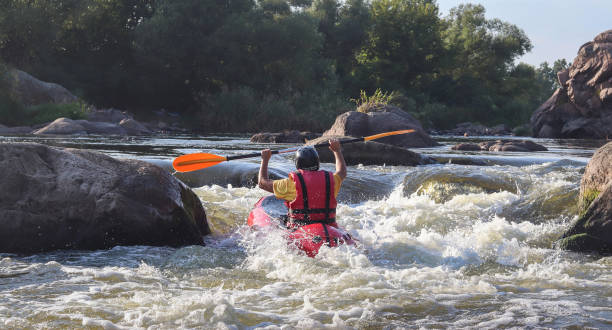 A man rowing inflatable packraft on whitewater of mountain river. Concept: summer extreme water sport, active rest, extreme rafting. stock photo