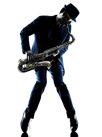 A handsome eleven year old African American boy playing the saxophone on a white background