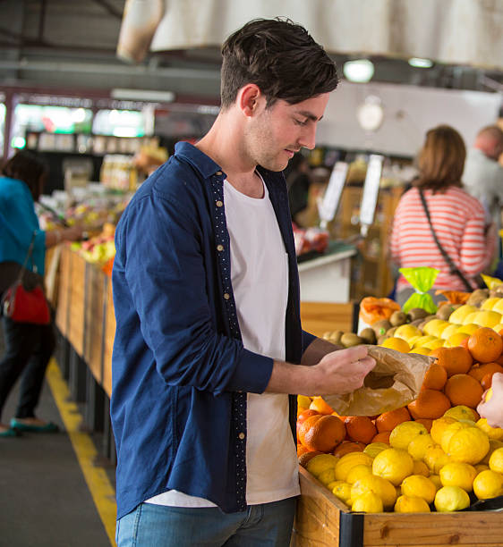 Man shopping for fruit Young adult man shopping for fruit at a market queen victoria market stock pictures, royalty-free photos & images
