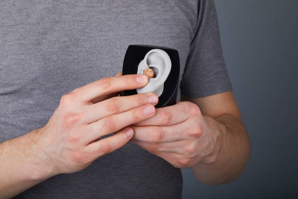 mężczyzna pokazujący korzystanie z aparatu słuchowego - hearing aids zdjęcia i obrazy z banku zdjęć