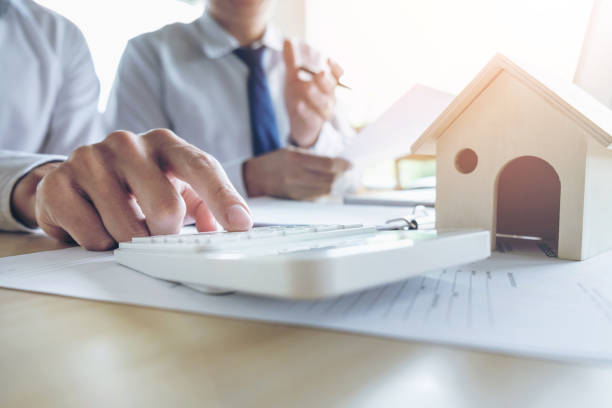 Man sign a home insurance policy on home loans, Agent holds loan investment chart graph documents and calculating table installment payment, Real Estate concept stock photo