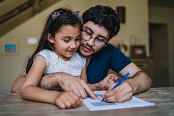 Man signing papers with daughter in his lap Handsome Latino man is sitting at a desk with daughter in his lap and signing papers. handwriting photos stock pictures, royalty-free photos & images
