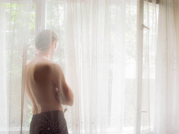 Man silhouette hiding behind tulle curtain stock photo