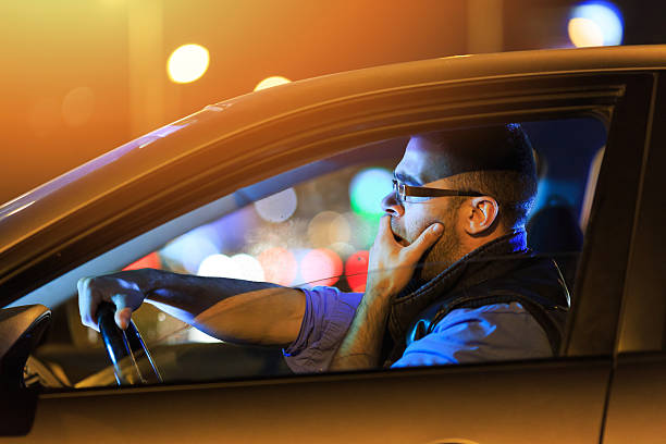 Man sitting in car and yawning by night stock photo