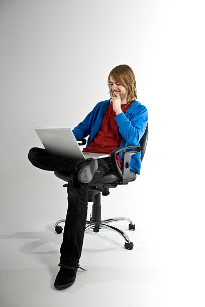 Man sitting in chair using laptop stock photo