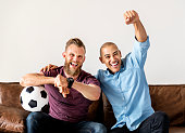 Man sitting together on a couch watching sport