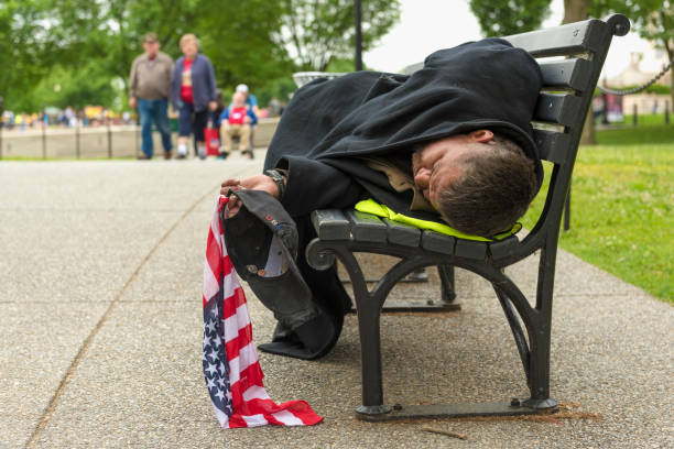 Man sleeping on a park bench in Washington DC whilst holding a Stars and Stripes flag stock photo