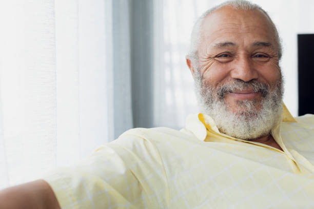 Man smiling inside a room Portrait close up of senior mixed race man smiling inside room. Authentic Senior Retired Life Concept senior men stock pictures, royalty-free photos & images