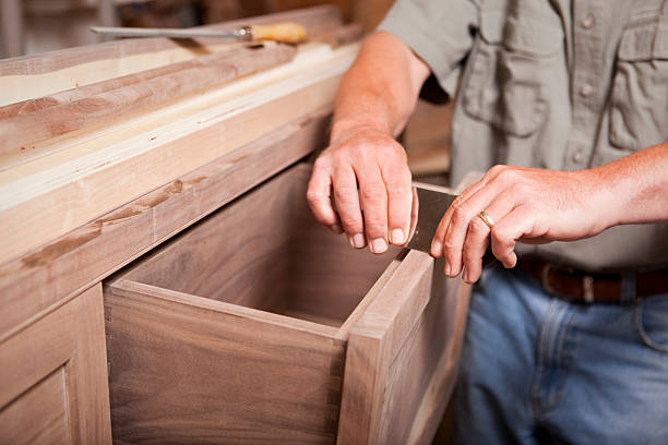 Man smoothing wood cabinet with scraper Carpenter/cabinet maker smoothing out a drawer top with a scraper. cabinet stock pictures, royalty-free photos & images