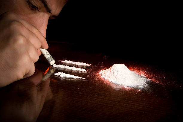 Man sniffing three lines of cocaine stock photo