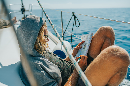 Man Solving Crossword Puzzle And Man Lying On Boat Stock Photo Download Image Now Istock
