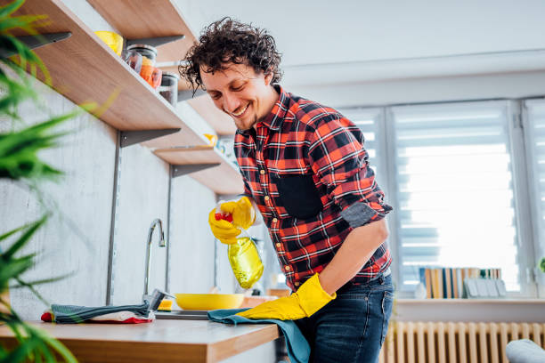 Man spraying kitchen counter and cleaning it stock photo