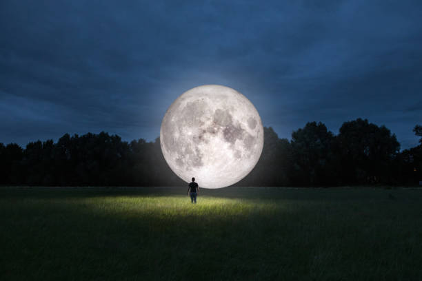 Man standing in front of moon Man standing in front of moon in a park at night. Photomanipulation of man standing in front of moon. moonlight stock pictures, royalty-free photos & images