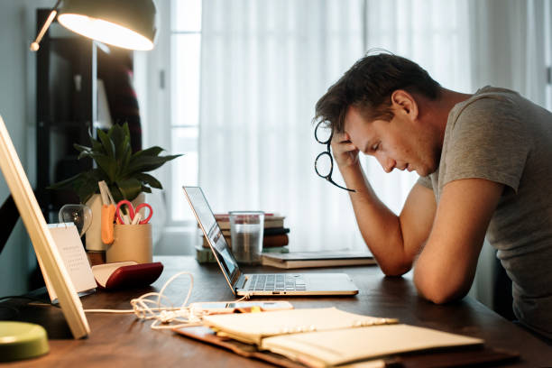 mens benadrukt tijdens het werken op de laptop - emotionele stress stockfoto's en -beelden