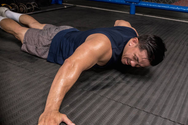 A man strugggles to do archer push-ups, a difficult and advanced variation at the gym. HIIT or calisthenics workout stock photo