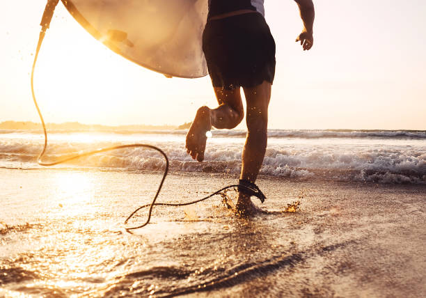 man surfer uitgevoerd in oceaan met surfboard. actieve vakantie, gezondheid levensstijl en sport concept image - branding stockfoto's en -beelden