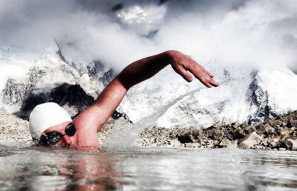 man swims in icy water with swimming  goggles and cap - ice swimming stockfoto's en -beelden