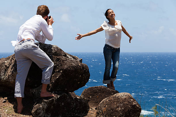 Man Takes Photo of Happy Woman on Hawaiian Cliffs stock photo