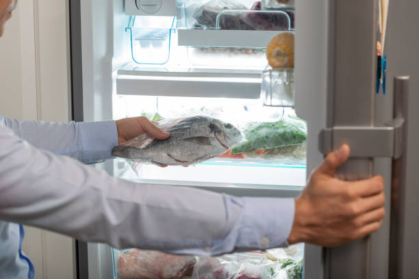 A man taking a fish into fridge stock photo