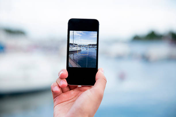 Man taking a photo with smart phone Hand taking a photo with smart phone. Picture of harbor with sailboats, seaside. Close-up nautical vessel photos stock pictures, royalty-free photos & images