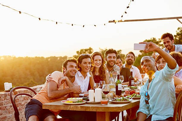 Man taking group selfie on mobile phone at party Smiling man taking group selfie on mobile phone at dinner party 30 39 years stock pictures, royalty-free photos & images