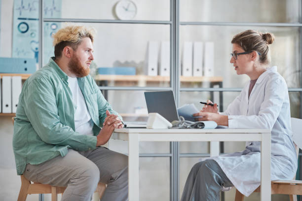 Man talking to the doctor at office stock photo