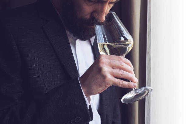 man tasting a glass of white wine - sniffing glass imagens e fotografias de stock