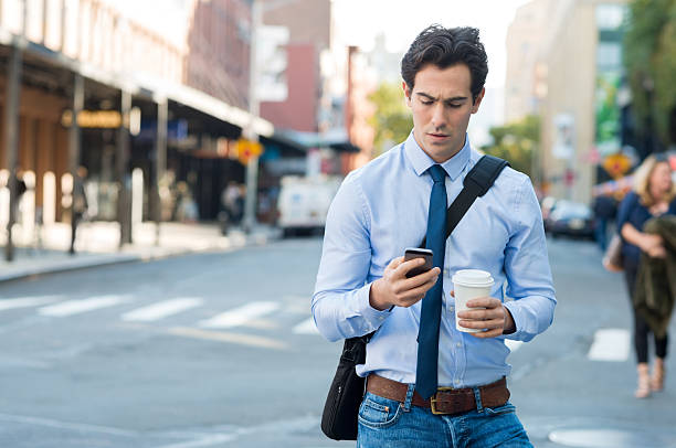 man texting on phone - walking with coffee stockfoto's en -beelden