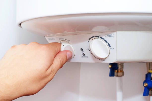 Man turns on the switch on control panel of home electric water heater (boiler). stock photo