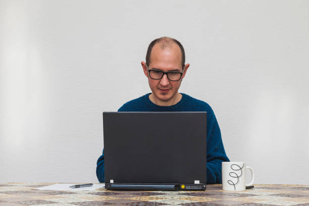 A man typing on a laptop stock photo