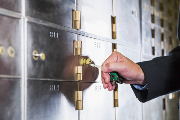 Man unlocking a safety deposit box Hand of a mature man opening a safety deposit box. He is turning the key in the lock. safes and vaults stock pictures, royalty-free photos & images