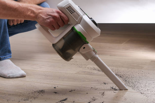 A man uses a bagless vertical cordless vacuum cleaner to clean floor. stock photo