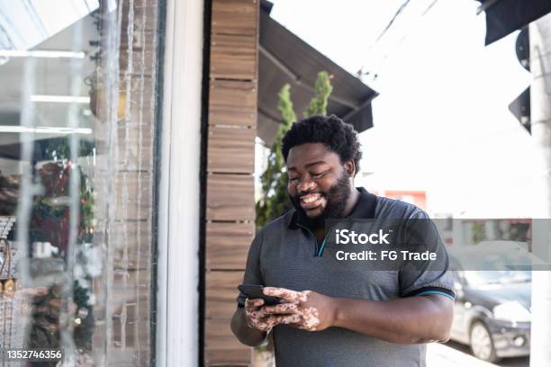 Man using a mobile phone beside a store window