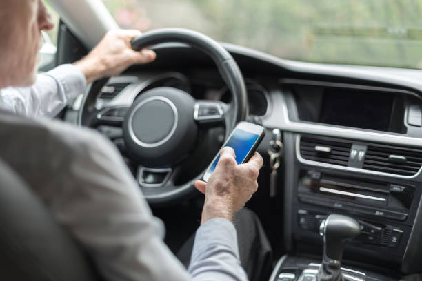 Man using a smartphone and driving stock photo
