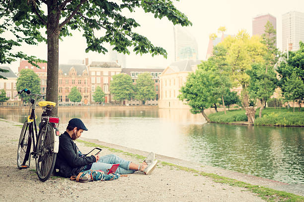 man using a tablet computer in the park. - zomer nederland stockfoto's en -beelden