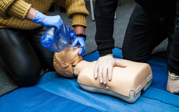 Man using CPR technique on dummy in first aid class. Oxigen mask on medical doll. stock photo