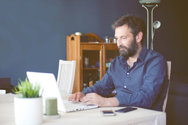 man using laptop while working from home stock photo