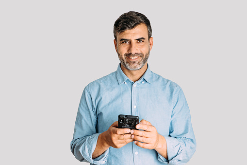 Portrait of man using smart phone and looking at camera on white background