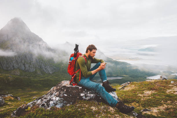 Man using smartphone hike in mountains travel blogger influencer lifestyle adventure vacations summer tour outdoor in Norway stock photo