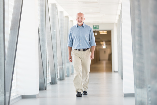 Full-length portrait of a man walking down the hallway inside a new building